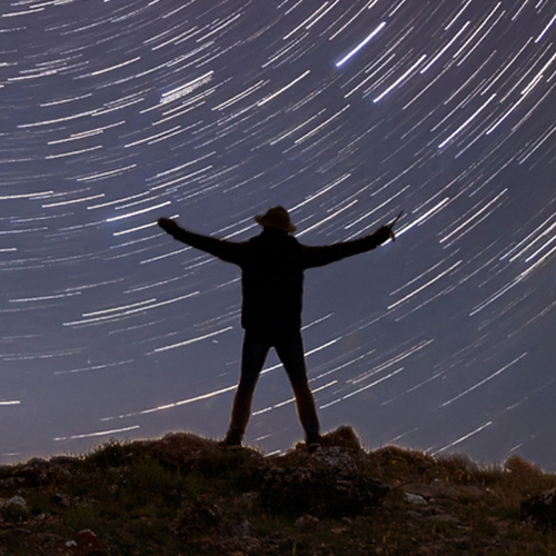 A man standing and facing a starry night sky