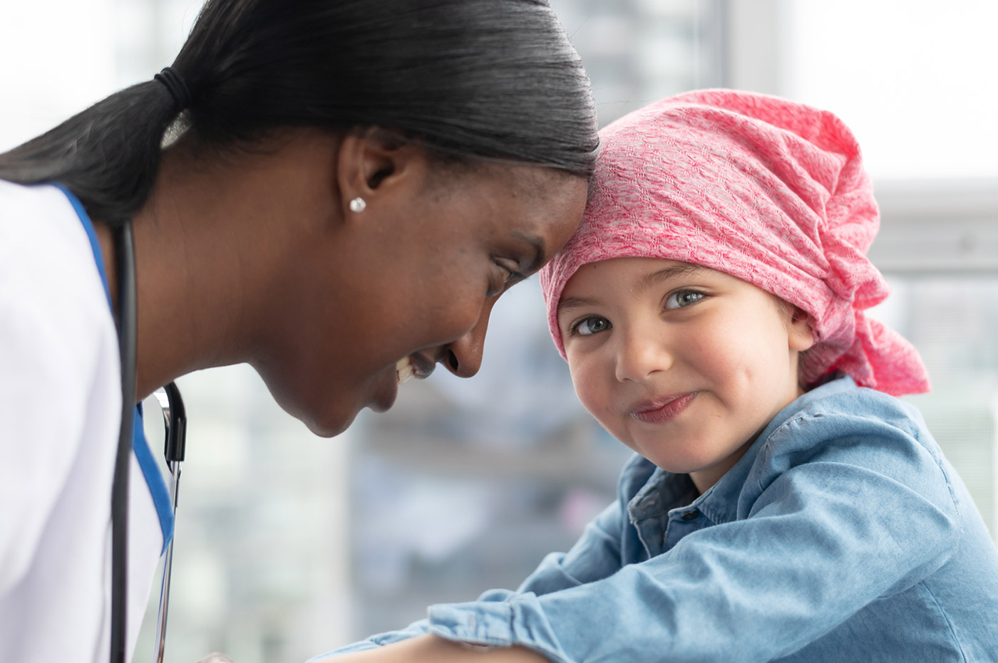 A female doctor with a young patient wearing a headscarf.